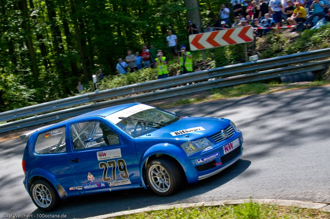 Der blaue VW Polo 6N2 Kit Car mit der Startnummer 279 in einer Kurve am Berg, dahinter Zuschauer an der Leitplanke
